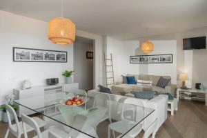 uma sala de estar com uma mesa de vidro e cadeiras brancas em Casa da Maresia em Porto Santo