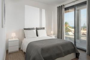 ein weißes Schlafzimmer mit einem Bett und einem großen Fenster in der Unterkunft Casa da Maresia in Porto Santo