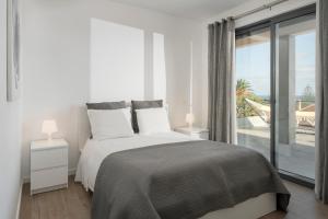 a white bedroom with a bed and a large window at Casa da Maresia by An Island Apart in Porto Santo
