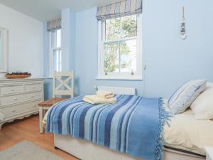 Dormitorio azul con cama y ventana en 15 Combehaven en Salcombe