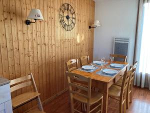 une table à manger avec des chaises et une horloge murale dans l'établissement Chalet Le Dévoluy, 3 pièces, 6 personnes - FR-1-504-676, à Saint-Étienne-en-Dévoluy