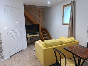 a living room with a yellow couch and a desk at Logis de l'Olivier in Asnières-sur-Nouère