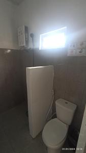 a bathroom with a white toilet and a window at ARIRANG27 HOMESTAY in Siborongborong