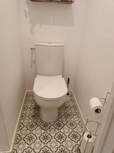 a white toilet in a bathroom with a tile floor at Logis de l'Olivier in Asnières-sur-Nouère