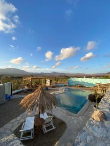 a pool with two chairs and a straw umbrella at Alegría Aire - Eco Retreat Finca Artis Tirma in Tarajalejo