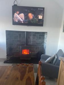 ein Wohnzimmer mit einem Kamin und einem Flachbild-TV in der Unterkunft Cosy Cottage Broadford in Broadford