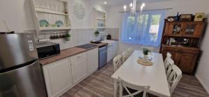 a kitchen with a white table and a refrigerator at Kékkút Cottage in Nagyvisnyó