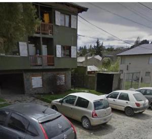 drie auto's geparkeerd op een parkeerplaats voor een gebouw bij Delta Home II in Bariloche