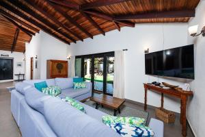 uma sala de estar com um sofá azul e uma televisão de ecrã plano em Hacienda del Mar em Tamarindo
