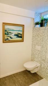 a bathroom with a toilet and a painting on the wall at Peaceful House & Garden (20min EU & City Center) in Brussels