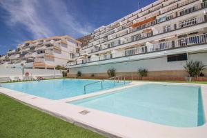 a large swimming pool in front of a building at Bright Amadores Seaview Apartment in Puerto Rico de Gran Canaria