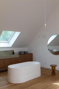 ein weißer Ottomane in einem Raum mit einem Spiegel in der Unterkunft Villa Léonard in Saint-Étienne-la-Thillaye