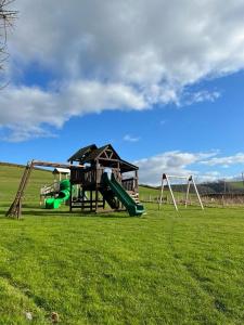 um parque infantil com dois escorregas e uma estrutura de jogos em Cuddfan em Llanrhystyd