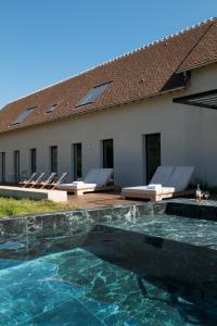 ein Swimmingpool mit Stühlen und einem Gebäude in der Unterkunft Villa Léonard in Saint-Étienne-la-Thillaye