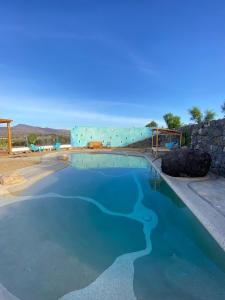 a swimming pool with blue water in front of a building at Tranquila Tierra - Eco Retreat Finca Artis Tirma in Tarajalejo