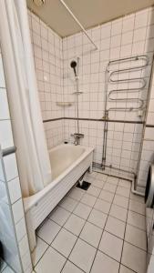a white tiled bathroom with a tub and a shower at FyraRumOasen in Gothenburg