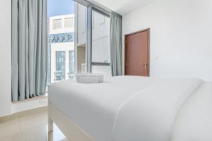 un letto bianco in una stanza con una grande finestra di WeHost - Modern 1BR Close to Burj Khalifa and Dubai Mall a Dubai