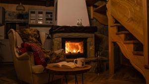 a fireplace in a living room with a chair and a book at Na Jeżynowej Polanie z gorącą balia in Wetlina