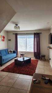 uma sala de estar com um sofá azul e um tapete vermelho em Casa Nueva en Condominio Tranquilo em Osorno