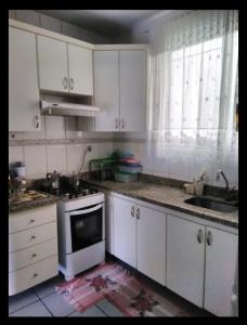 a kitchen with white cabinets and a sink and a stove at Apartamento praia de Camburi in Vitória