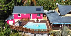 - une vue aérienne sur une maison rose avec une piscine dans l'établissement Kaz Kalina - Gîtes avec piscine partagée, à Bouillante