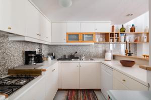 a white kitchen with white cabinets and a sink at Athenian Getaway Villa in Plaka with Acropolis View by Athenian Homes in Athens
