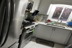 uma cozinha com um frigorífico de aço inoxidável e um lavatório em ShayCozyDelux-Room-101 em Pickering