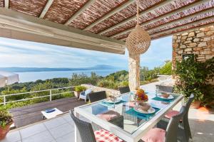 un patio con tavolo in vetro e sedie sul balcone. di Luxury villa in Kechria a Kechria