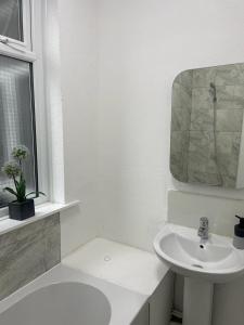 a white bathroom with a sink and a mirror at Three En-Suit Rooms in Manchester