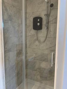a shower with a glass door with a shower head at Three En-Suit Rooms in Manchester