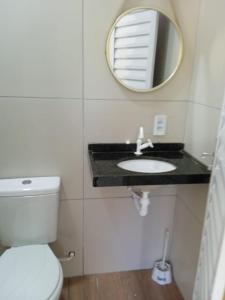 uma casa de banho com um WC branco e um espelho. em Pousada Vista Verde em Paracuru