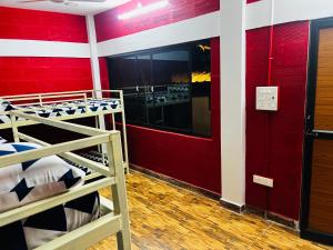 Cette chambre comprend 2 lits superposés et un mur rouge. dans l'établissement Hostel kuruku santhu colive, à Pondichéry