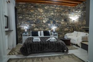 1 dormitorio con cama y pared de piedra en kaimak luxury chalet en Palaios Agios Athanasios