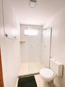uma casa de banho branca com um WC e um chuveiro em Condomí. Praia da Pérola -Beira Mar-Ilhéus/Itacaré em Ilhéus