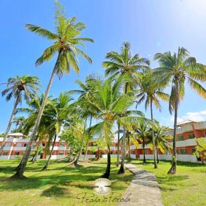 uma fila de palmeiras em frente a um edifício em Condomí. Praia da Pérola -Beira Mar-Ilhéus/Itacaré em Ilhéus