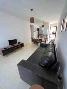 uma sala de estar com um sofá de couro preto e uma mesa em Condomí. Praia da Pérola -Beira Mar-Ilhéus/Itacaré em Ilhéus