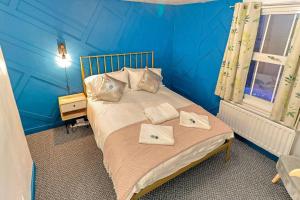 a blue bedroom with a bed with towels on it at Beautiful 3-Bed Cottage in Burnham-on-Crouch in Burnham-on-Crouch