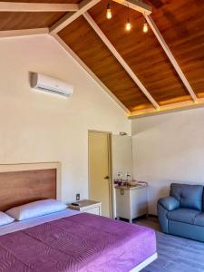 1 dormitorio con cama morada y sofá en RIO HOTEL Y GLAMPING, en Jalpan