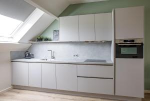 uma cozinha com armários brancos e uma janela em Barn24 - The Stable & The Loft em Roggel
