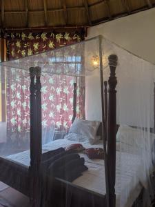 1 dormitorio con cama con dosel y ventana en Cwmbale Eco-Safari Lodges, Restaurant and Zoo., en Mbale