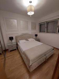Un dormitorio con una cama grande y una lámpara de araña. en Jana aprtment Budva en Budva
