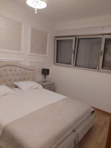 a bedroom with a white bed and two windows at Jana aprtment Budva in Budva