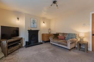 a living room with a couch and a flat screen tv at Broomfield Cottage Nr Pickering - DOGS STAY FOR FREE in Pickering