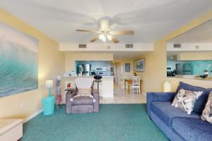 a living room with a blue couch and a ceiling fan at Cape Palms in Cape Canaveral