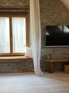 Sala de estar con asiento junto a la ventana y TV en Casa Neste: Grange rénovée haut de gamme, en Arreau