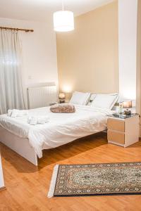 1 dormitorio con 1 cama blanca grande y 1 alfombra en Διαμέρισμα στη χλόη Καστοριάς en Kastoria