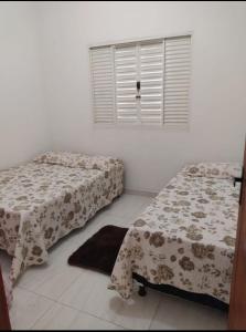 a bedroom with two beds and a window and a rug at Rancho lago azul in Guapé