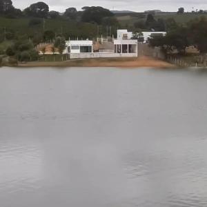 a large white building next to a body of water at Rancho lago azul in Guapé
