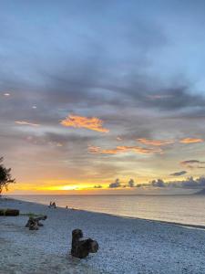 una puesta de sol en una playa con rocas en la playa en Nana's Beach Surigao, en Surigao