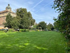 a large field of green grass with a building at Apartment in historical center with park view in Plzeň